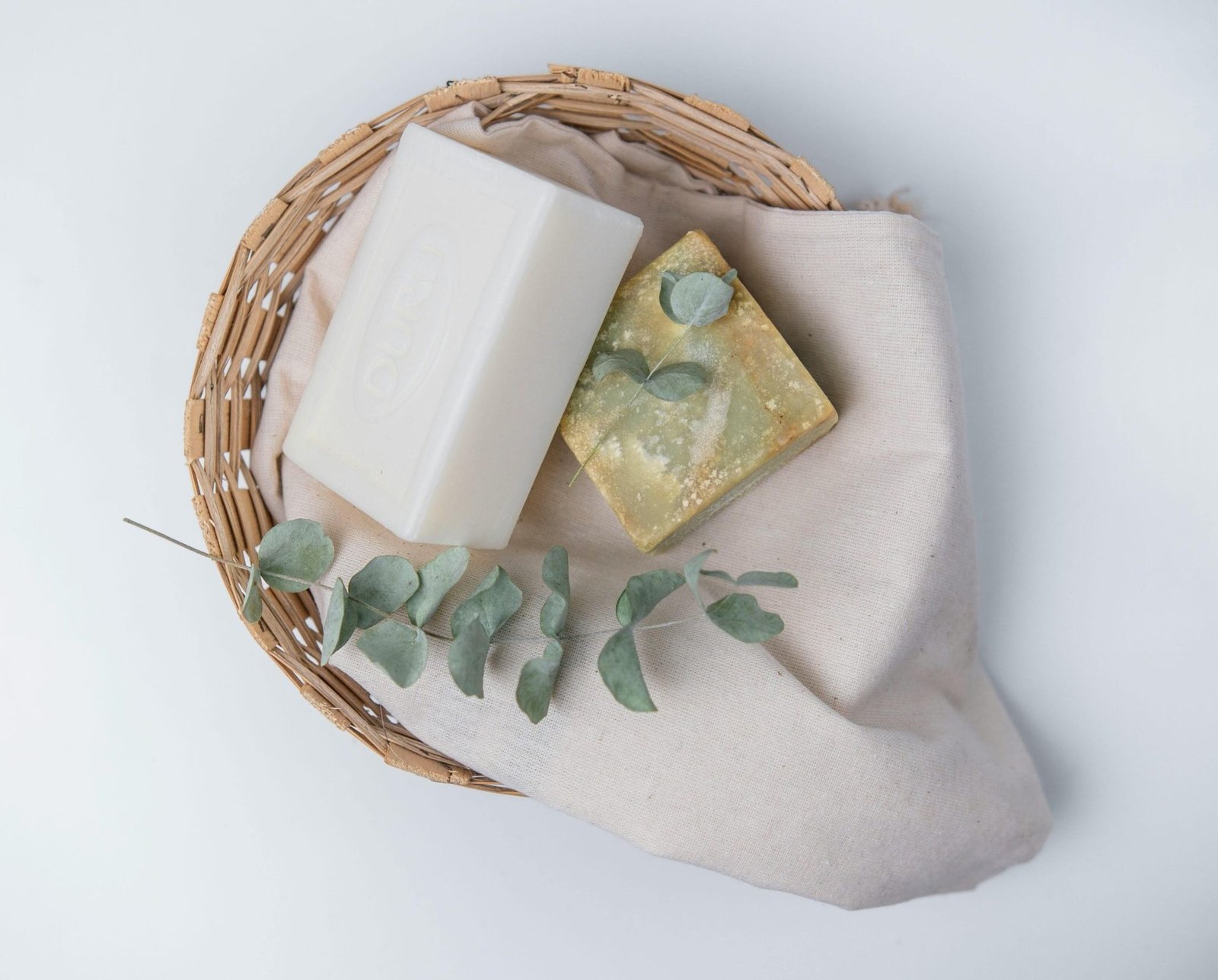 A natural, eco-friendly soap set with eucalyptus in a wicker basket, perfect for organic lifestyle promotions.
