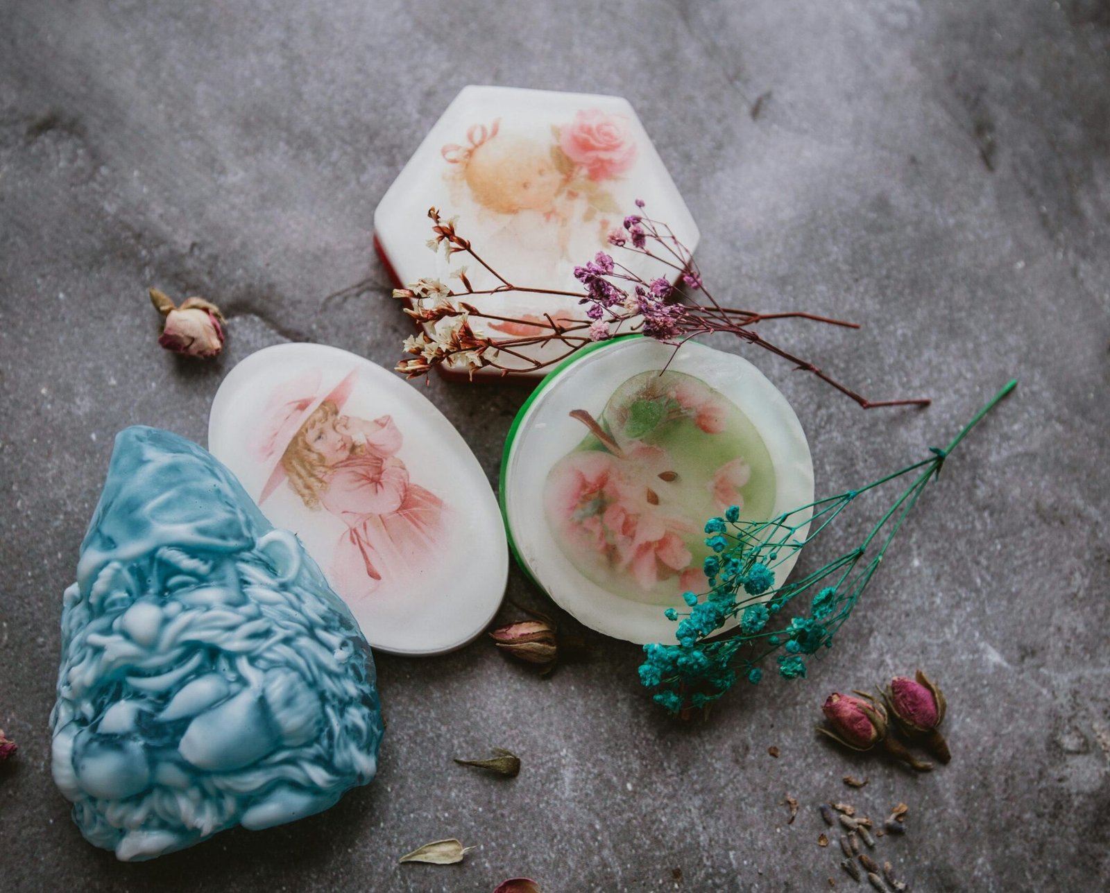 Top view of creative aromatic handmade soaps arranged on gray surface with colorful dried flowers and herbs